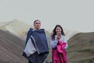 一对男女裹在睡袋里，在山区地形中享受自然和户外露营