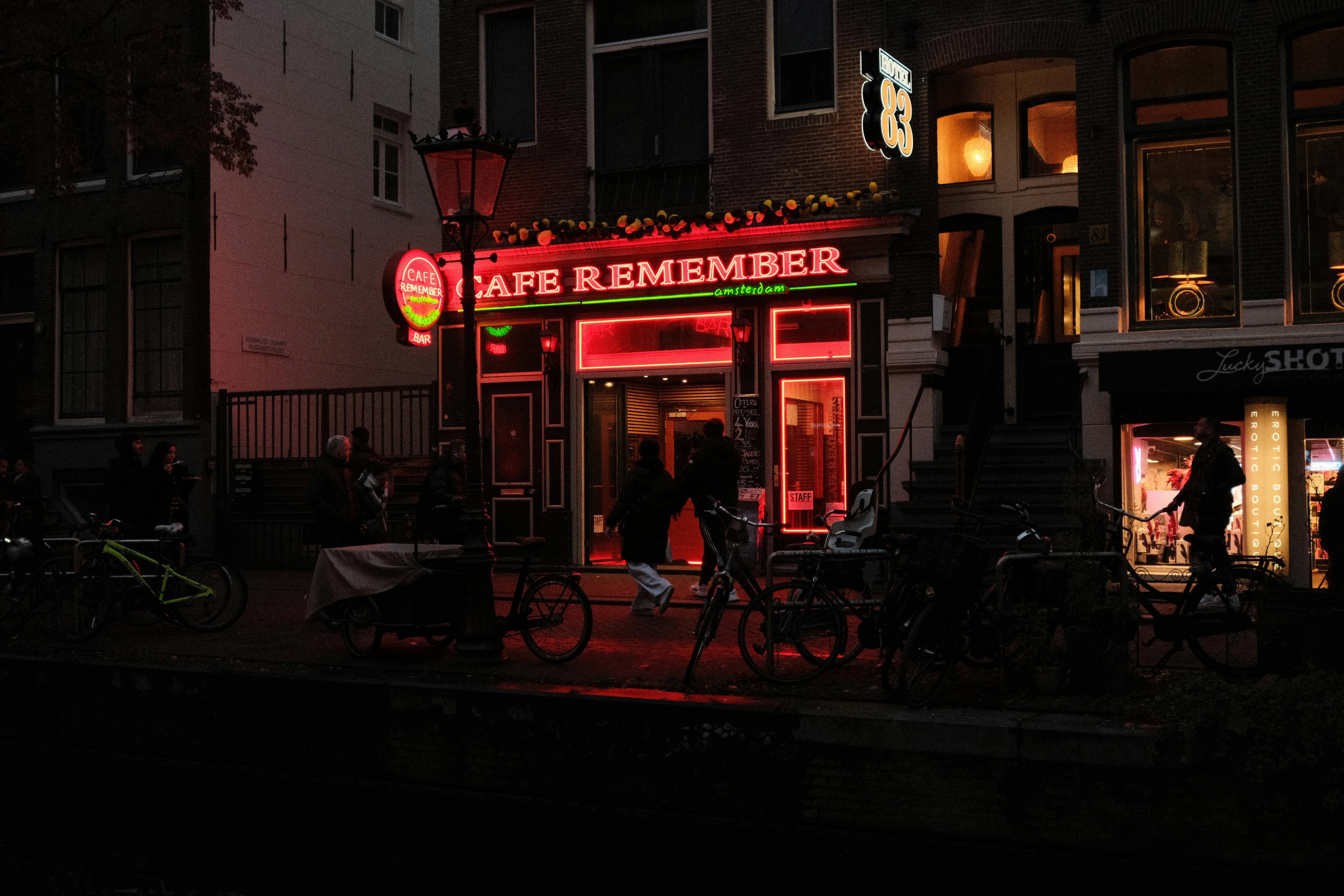 Amsterdam'da kanal kenarında bisiklet süren insanlar ve açık hava kafelerinde sosyalleşen genç profesyonellerle şehrin canlı sosyal yaşamı.