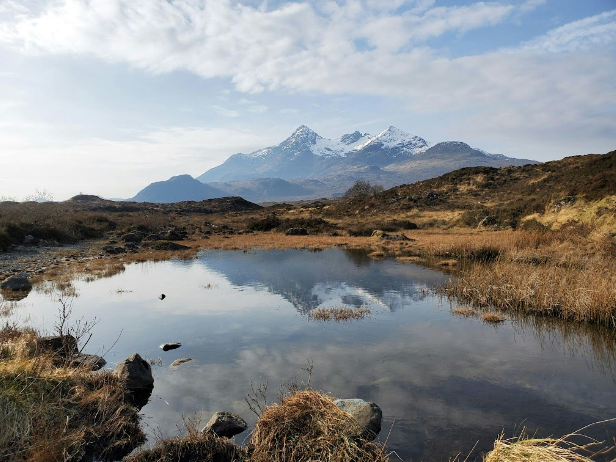 Peaceful loch reflecting snow-capped mountains in the Scottish Highlands.