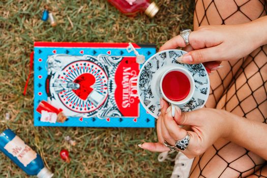Tea party scene with Alice in Wonderland book and vibrant visuals, outdoors.