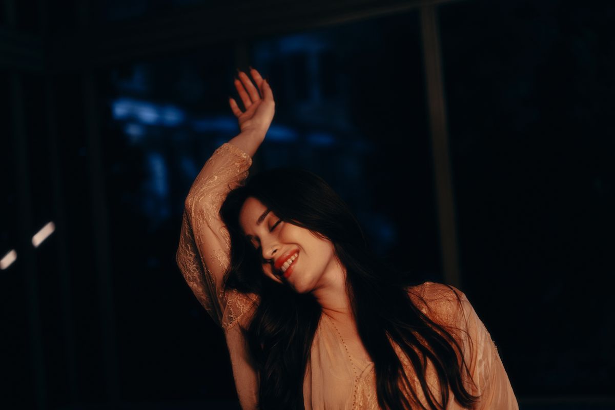 Woman with a calm expression resting indoors in soft evening light