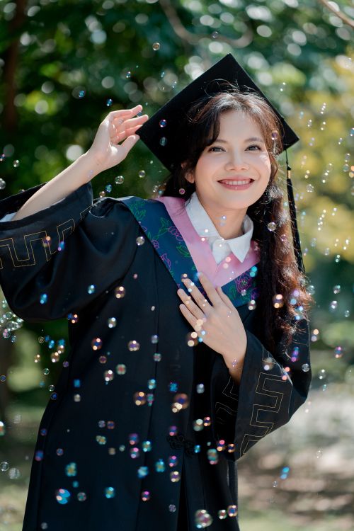 Free Happy graduate celebrating with bubbles in a sunny outdoor setting. Stock Photo