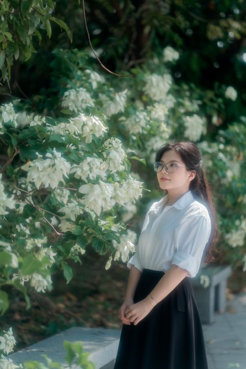 Free Woman in white blouse in garden with lush white flowers, captured in soft light. Stock Photo