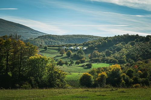 Free Charming landscape with rolling hills and cottages under a clear blue sky. Stock Photo
