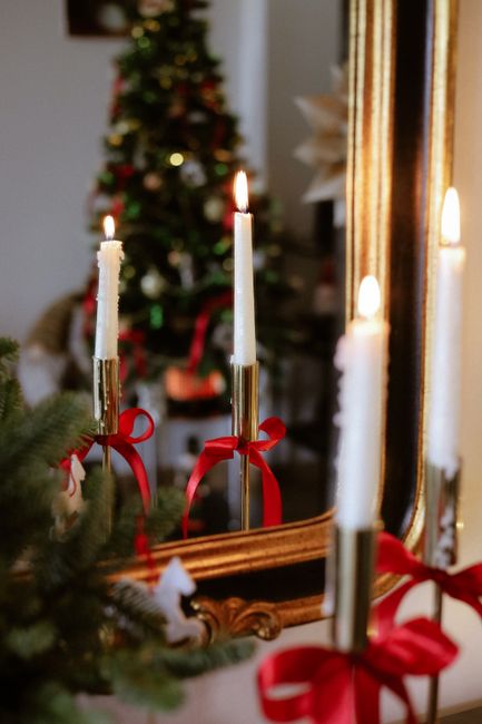Festive candle arrangement with Christmas tree reflection creates warm holiday ambiance.