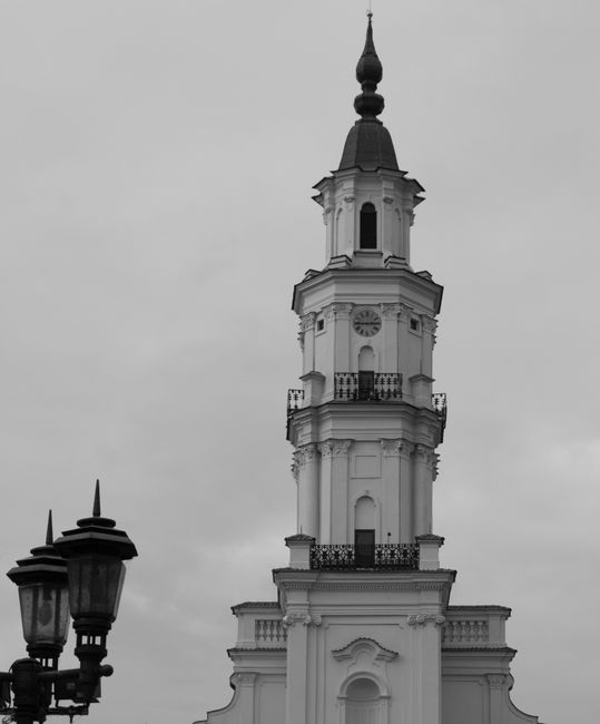 Monochrome image of a historic clock tower with ornate details under a cloudy sky.