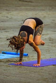 A woman practices yoga on Arambol Beach in Goa, showcasing balance and strength.