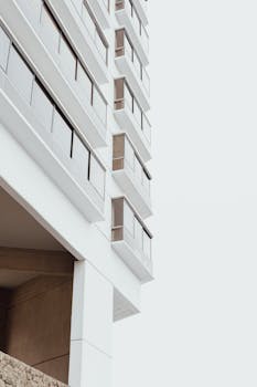 Vertical shot of a modern white high-rise apartment building against a clear sky.