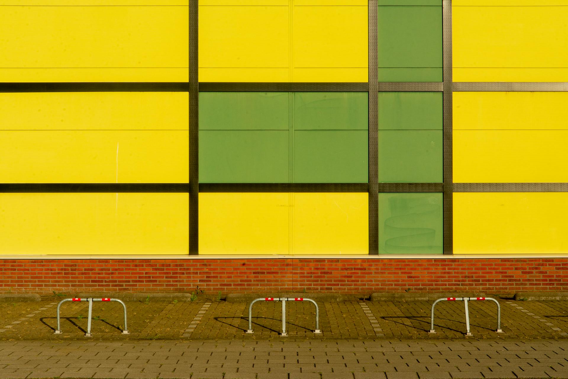 Colorful building facade with bike racks in an urban setting, featuring vibrant yellow and green panels.