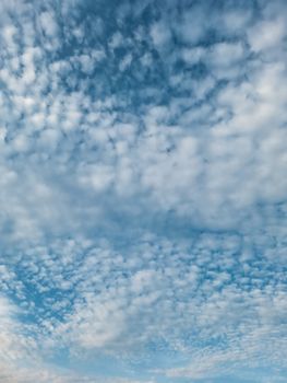 Beautiful image of blue sky with scattered white clouds creating a serene pattern.