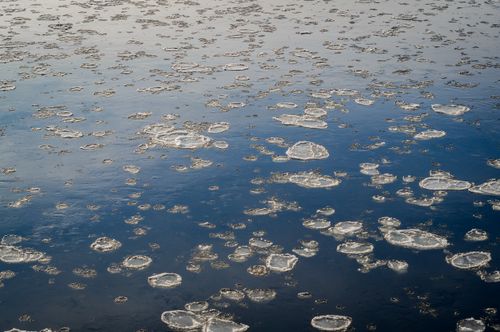 Free An aerial view of scattered floating ice on tranquil blue water, evoking a cold and serene atmosphere. Stock Photo