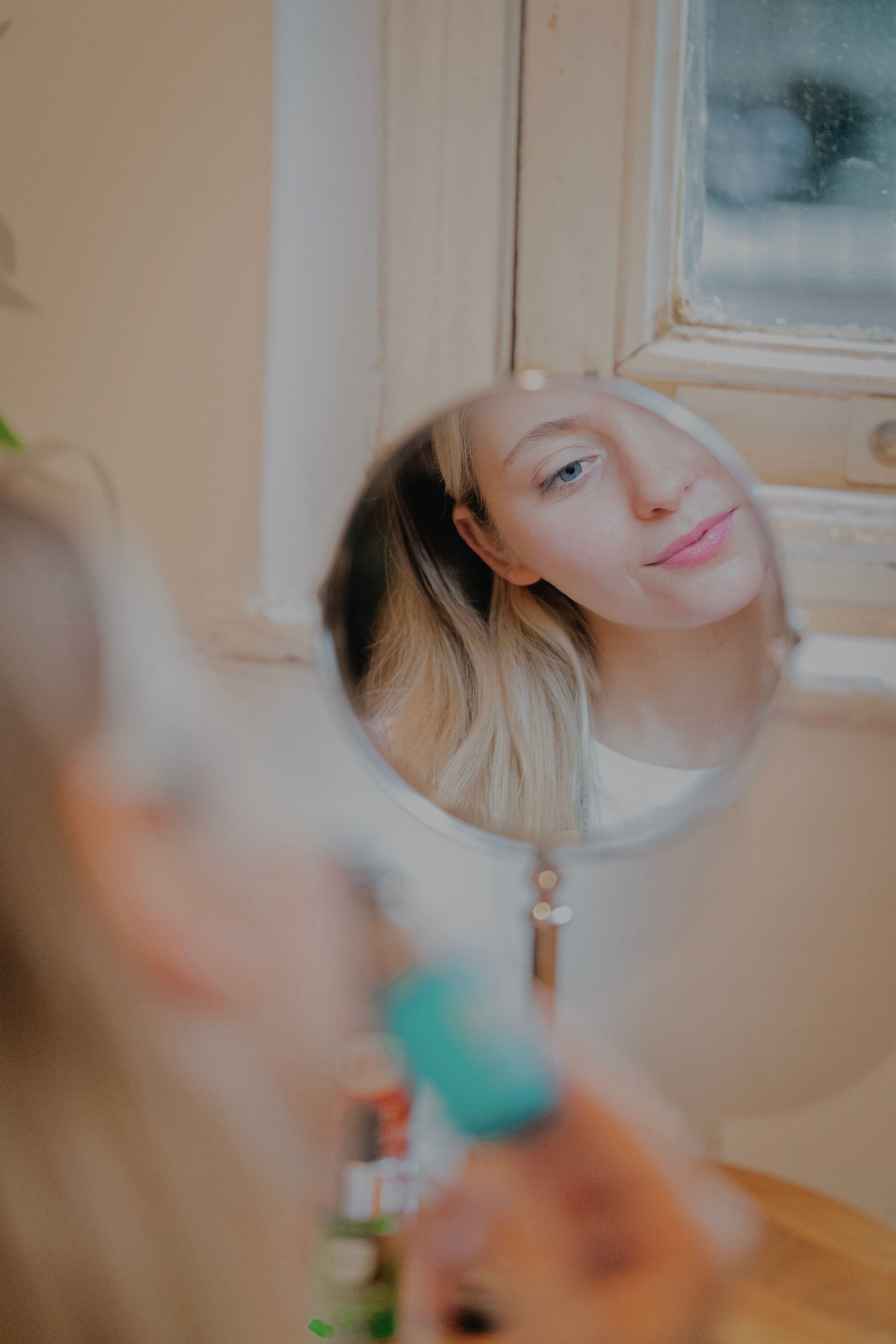 Gratuit Une femme se maquillant devant un miroir, reflétant une expression sereine et concentrée. Photos