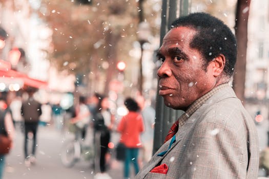 一个男人站在繁华的城市街道上，在柔和的降雪中，画面以温暖的色调被捕捉