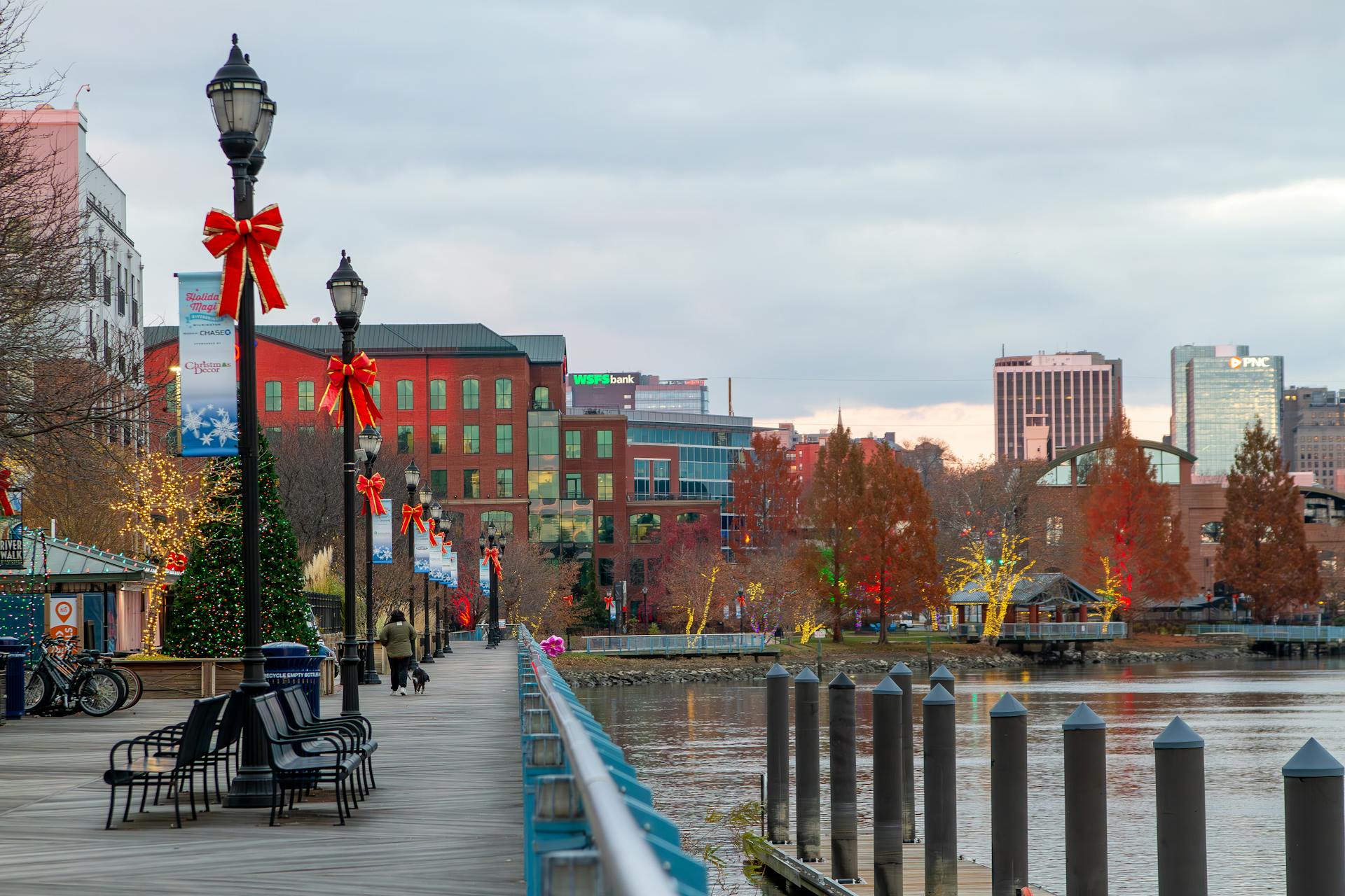 Festively decorated Wilmington riverfront with holiday lights and bows along the walkway.