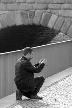 Black and white photo of a man taking a picture of a bridge in Madrid.