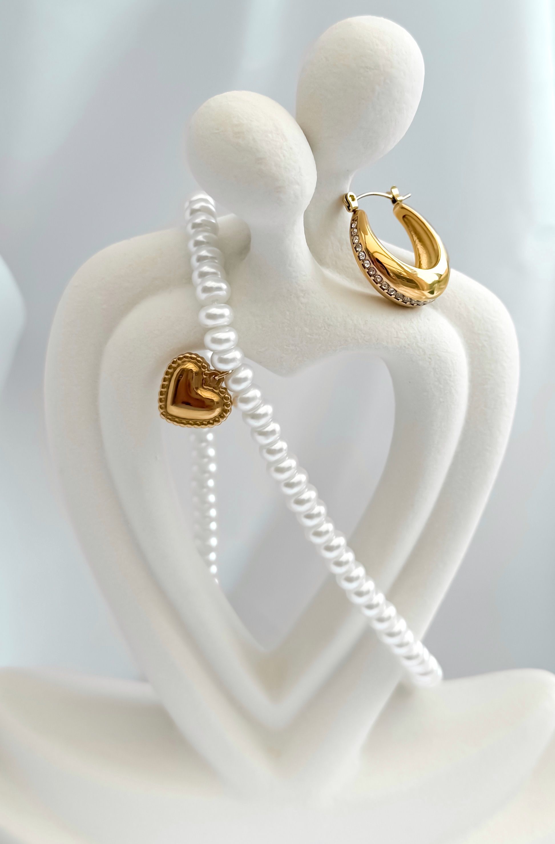 White sculpture with pearl and gold jewelry in heart shape design, ideal for elegant decor.