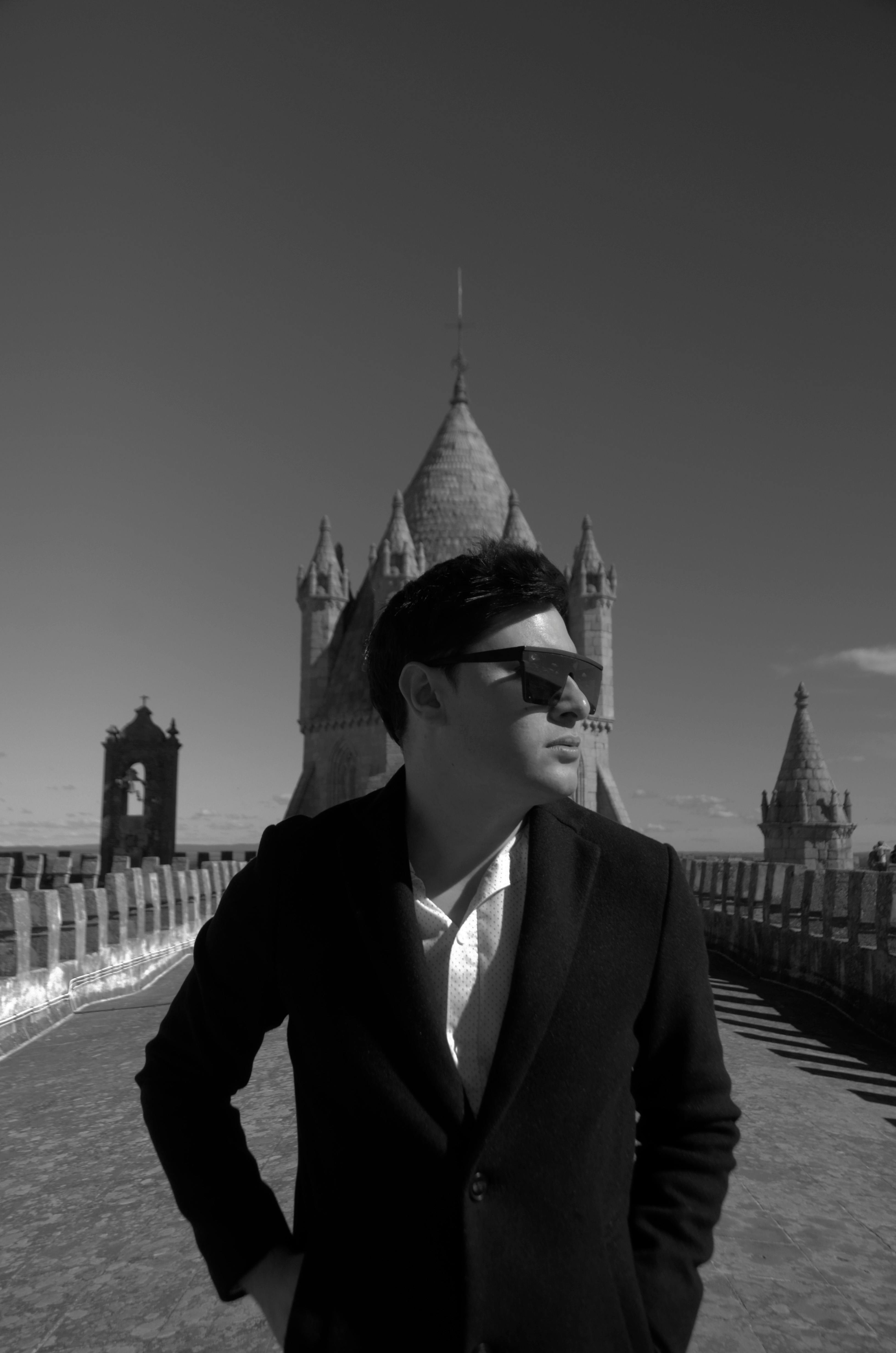 stylish man posing on rooftop with gothic architecture