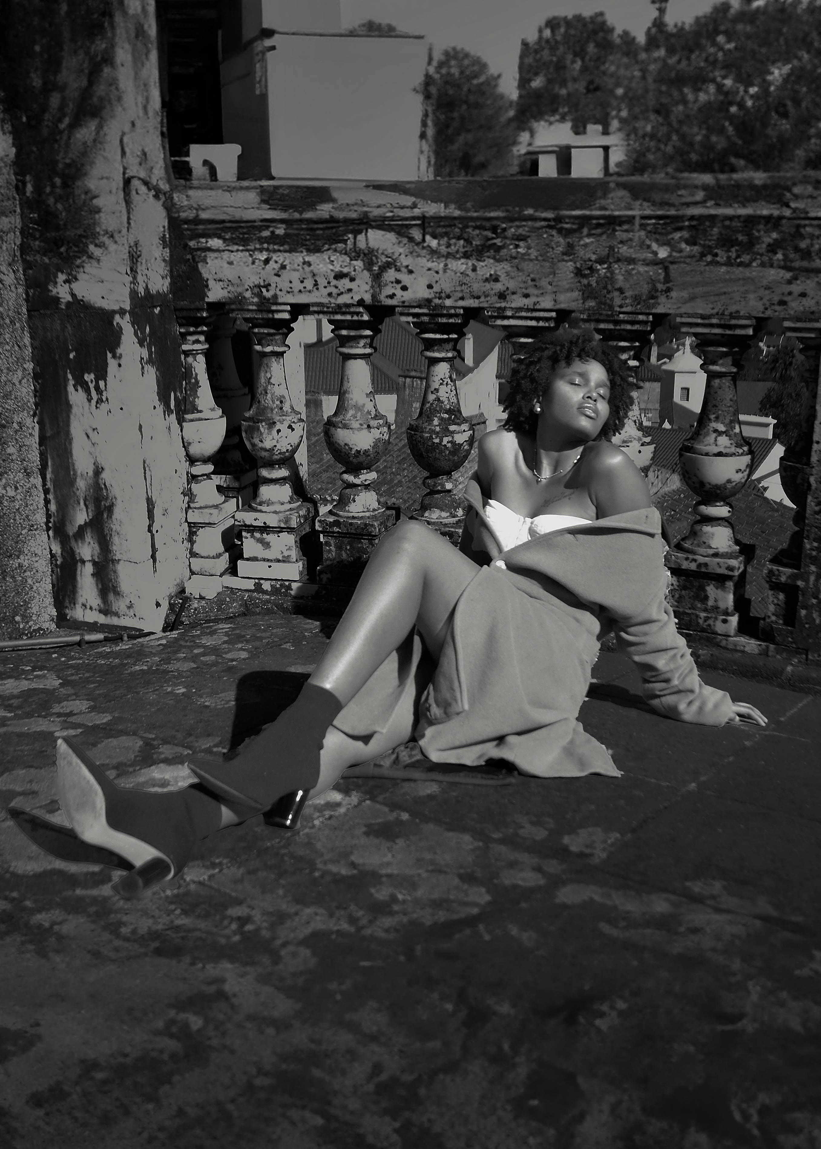 Безкоштовне Модна жінка відпочиває на балконі, обіймаючи сонячне світло на чорно-білому фото. стокове фото