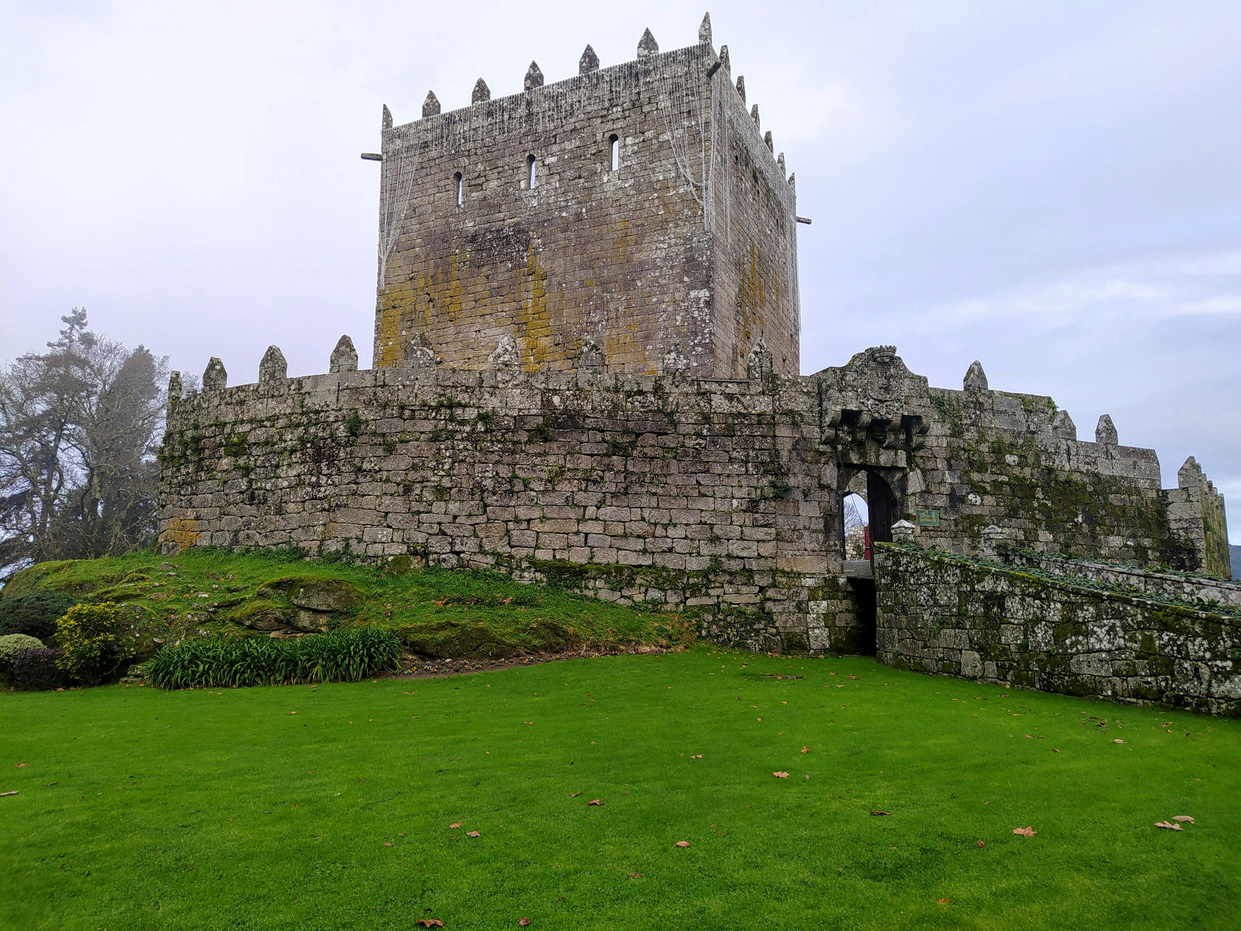 Historic stone castle in Salvatierra de Miño, showcasing medieval architecture against a green landscape.