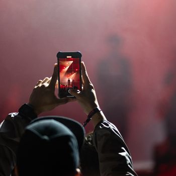 A person records a live concert, capturing exciting stage performances on their smartphone.