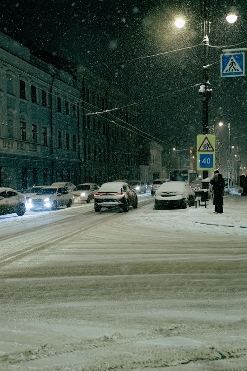 Free A city street at night during heavy snowfall, with cars and pedestrians. Stock Photo