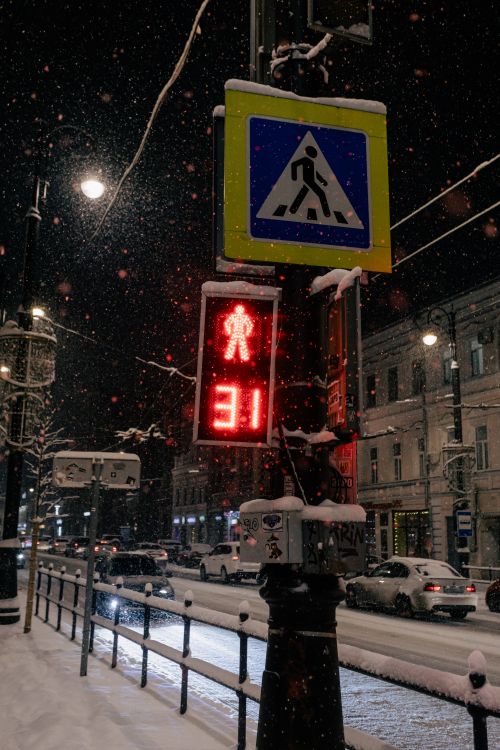 Free Wintry city street at night with pedestrian crossing and snow falling. Stock Photo