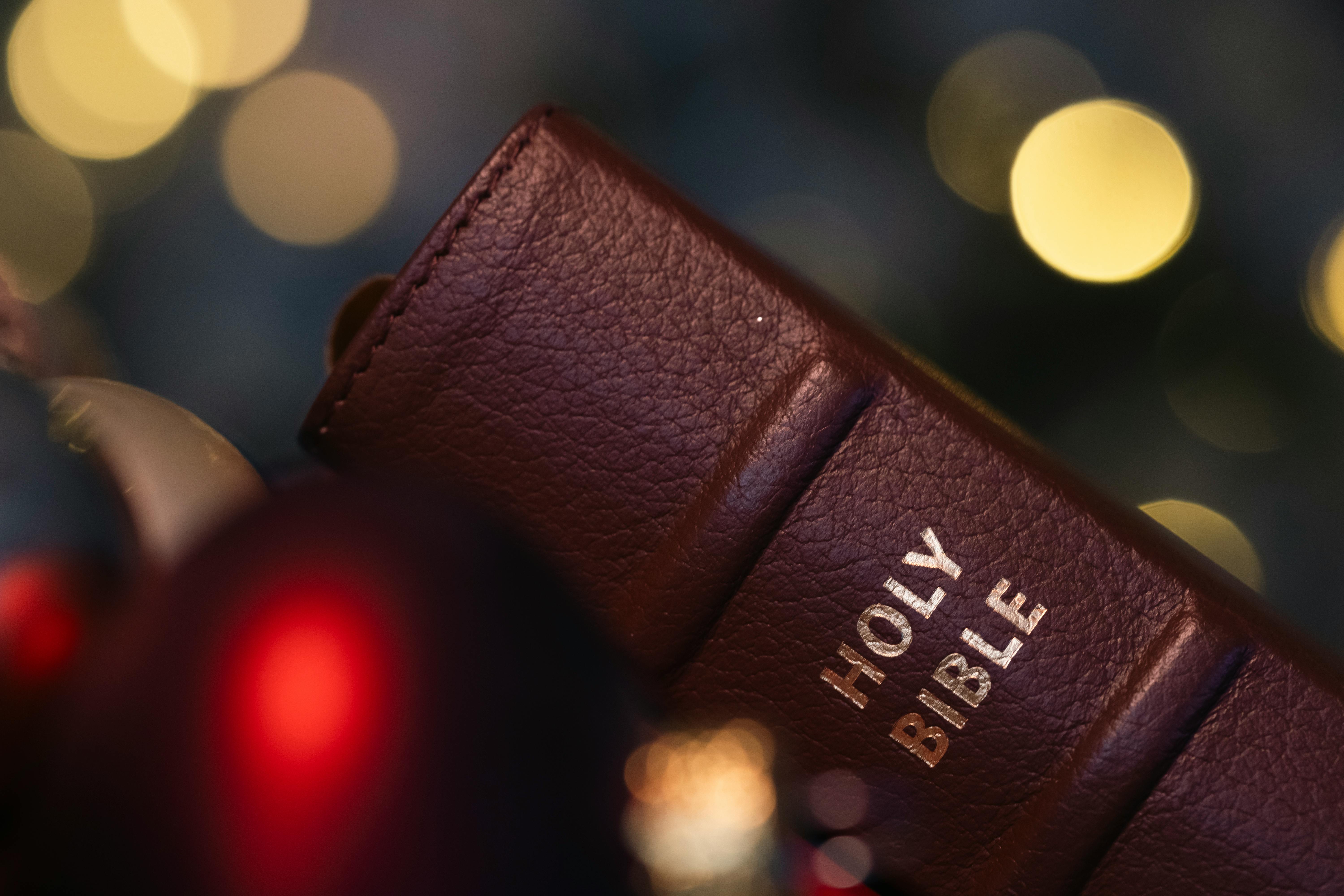 Close-up of a brown leather Holy Bible against a festive blurred lights backdrop.