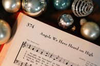 Sheet music for 'Angels We Have Heard on High' with Christmas ornaments.