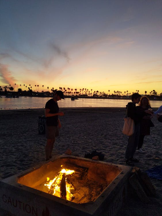 Few People on Beach Near Bonfire during Night Time