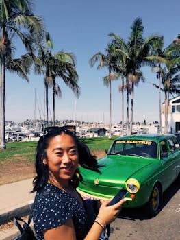 一位开朗的女子在圣地亚哥阳光明媚的码头边，与一辆绿色电动汽车合影