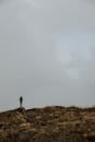 在法国梅泽尔的草地山顶上，一位孤独的徒步旅行者站在喜怒无常的多云天空下