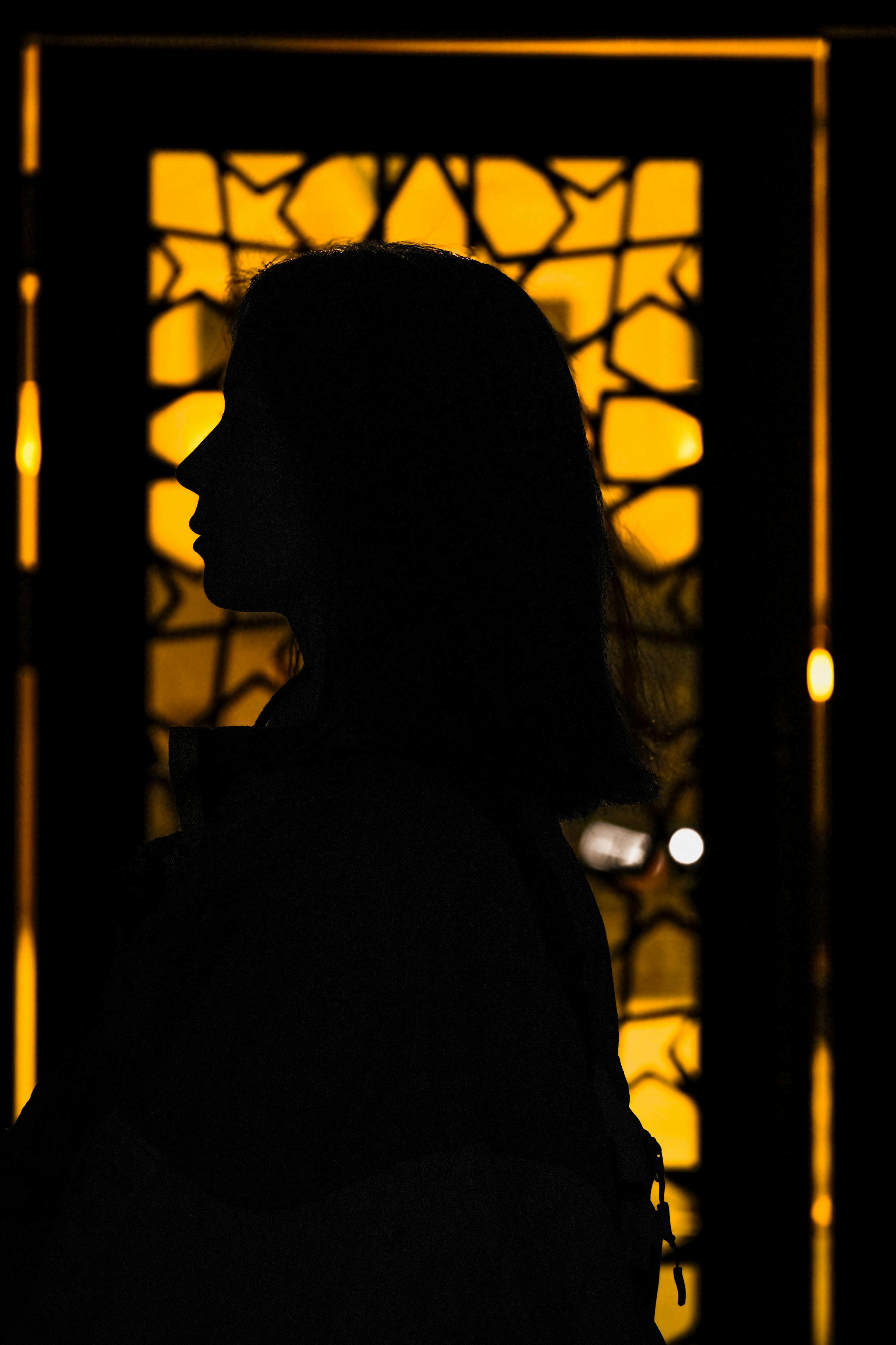 Kostenlos Silhouette einer Frau vor einem beleuchteten Buntglashintergrund. Stock-Foto