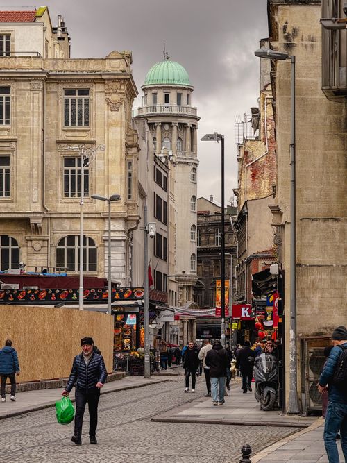Free Bustling city street lined with historic buildings under cloudy skies. Stock Photo