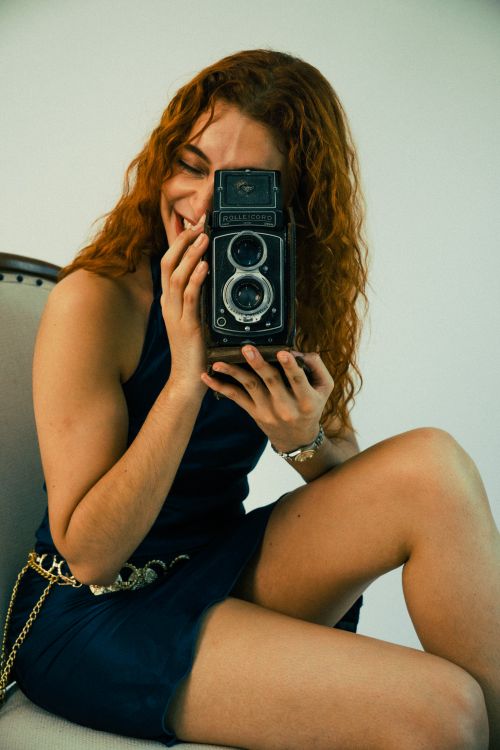 Free Young woman holds a vintage camera, expressing joy in an indoor setting. Stock Photo