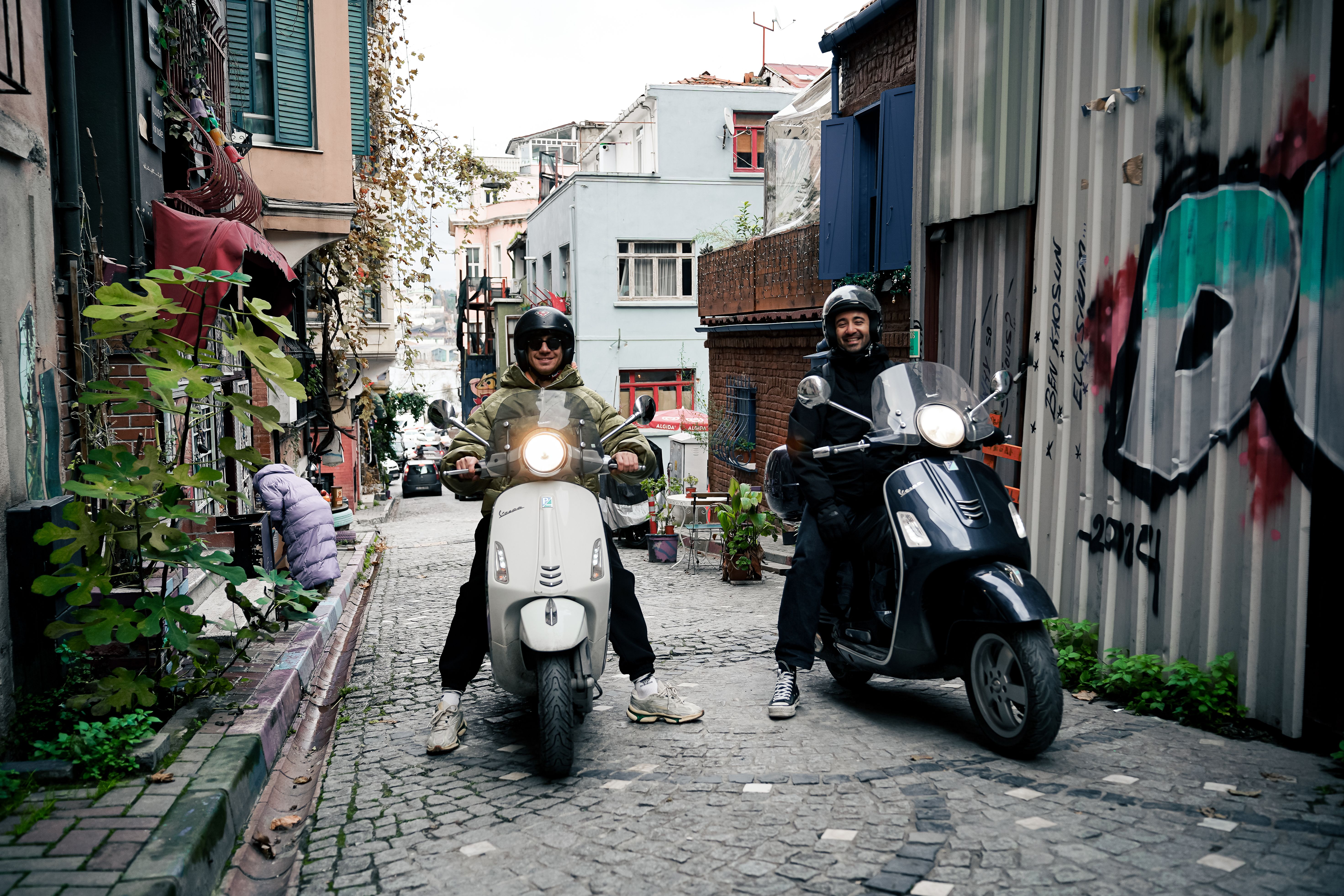 Two Riders on Scooters in Vibrant Urban Alley · Free Stock Photo