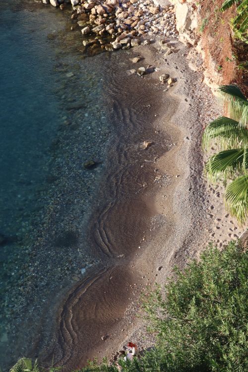 Free Aerial shot of a tranquil beach with rocks and clear blue water, perfect for summer escapes. Stock Photo