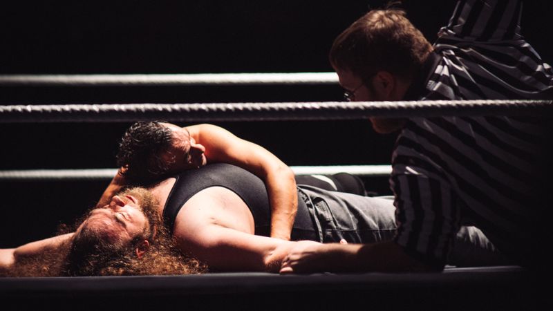 Intense wrestling match showcasing a dramatic pinfall with referee counting.