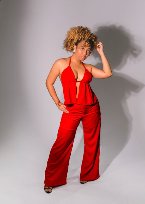 Free Confident woman posing in a vibrant red outfit in a studio setting. Stock Photo