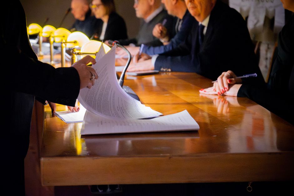Primer plano de una mesa de reunión de negocios con documentos siendo revisados y firmados en Bérgamo, Italia.