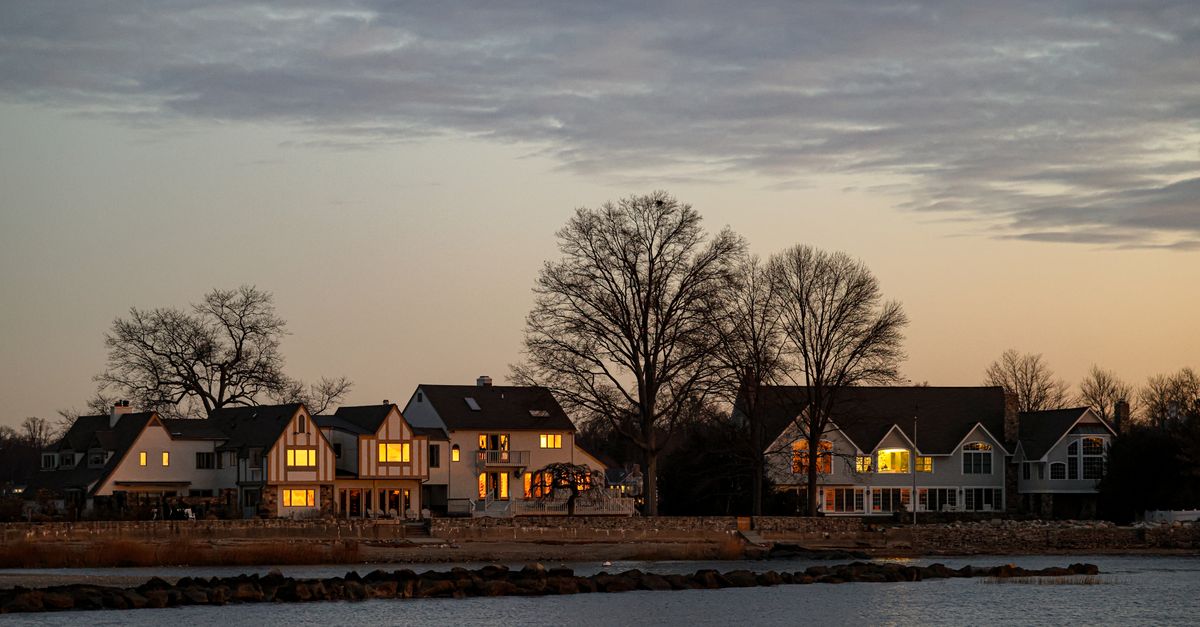 Serene view of waterfront homes at sunset in Stamford, Connecticut, featuring calm water and dramatic skies.