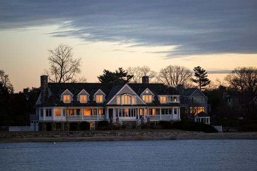 Elegant waterfront home in Stamford, Connecticut, captured at twilight with glowing windows and serene surroundings.