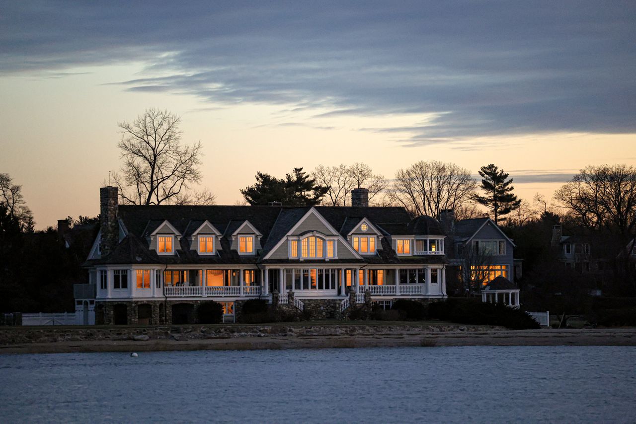 Elegant waterfront home at twilight with glowing windows