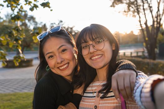 Two friends enjoy a sunset moment outdoors with happy smiles.
