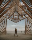 黄昏时分，一个人站在广阔沙漠中的大型木制框架下，宛如一座标志性的艺术装置