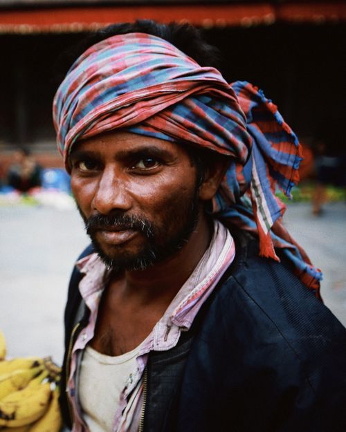 Free Close-up portrait of a man wearing a colorful striped headscarf, captured outdoors in natural light. Stock Photo