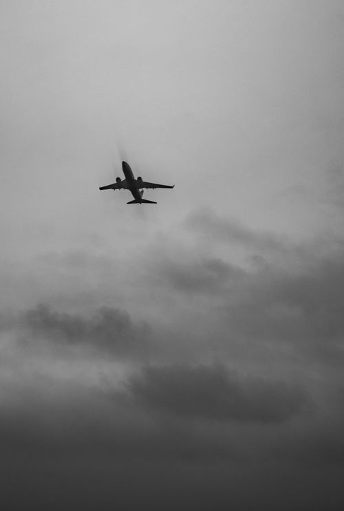 Free Silhouette of an airplane against a dramatic cloudy sky in black and white. Stock Photo