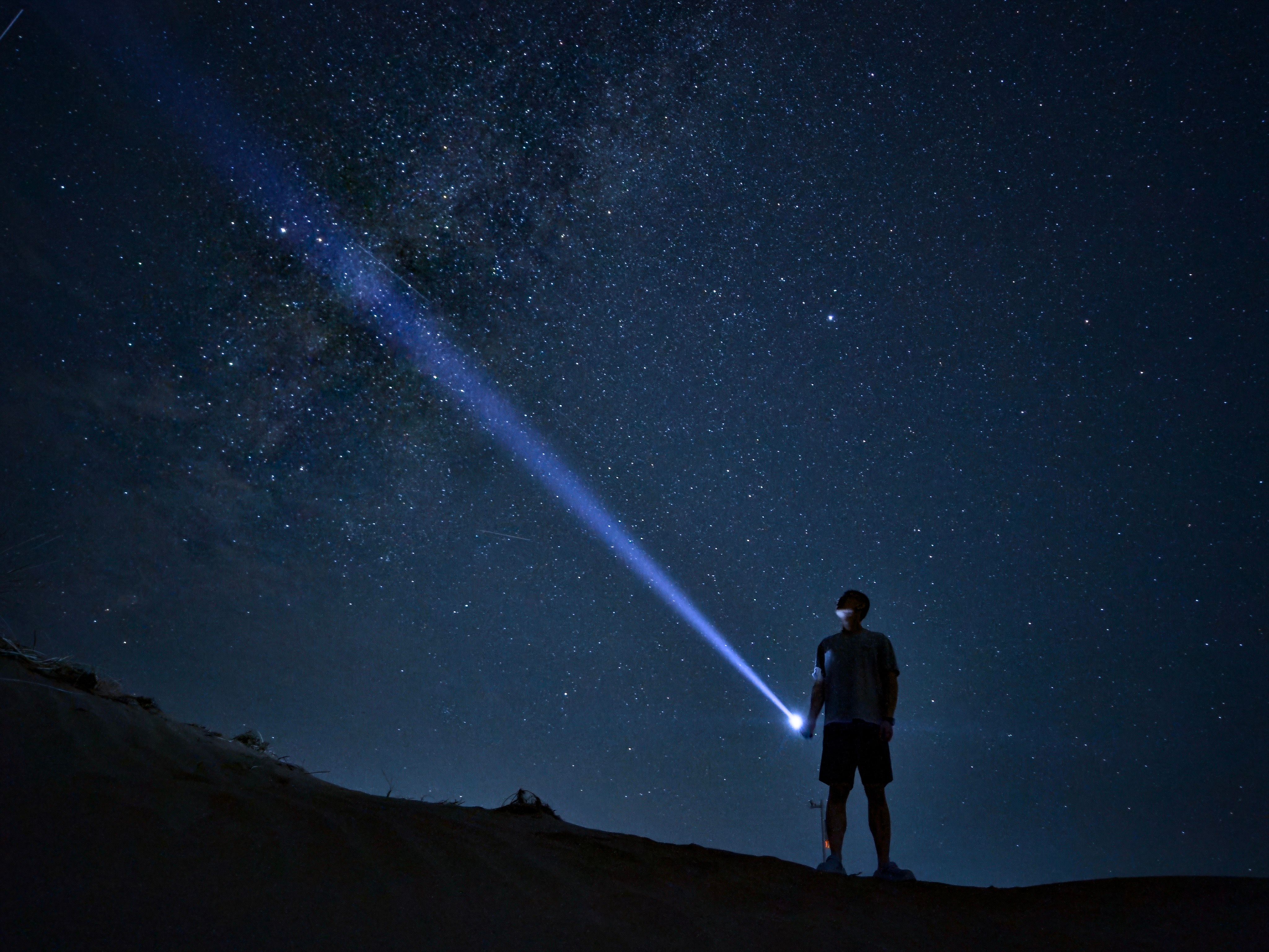 Man with Flashlight Under Starry Night Sky · Free Stock Photo