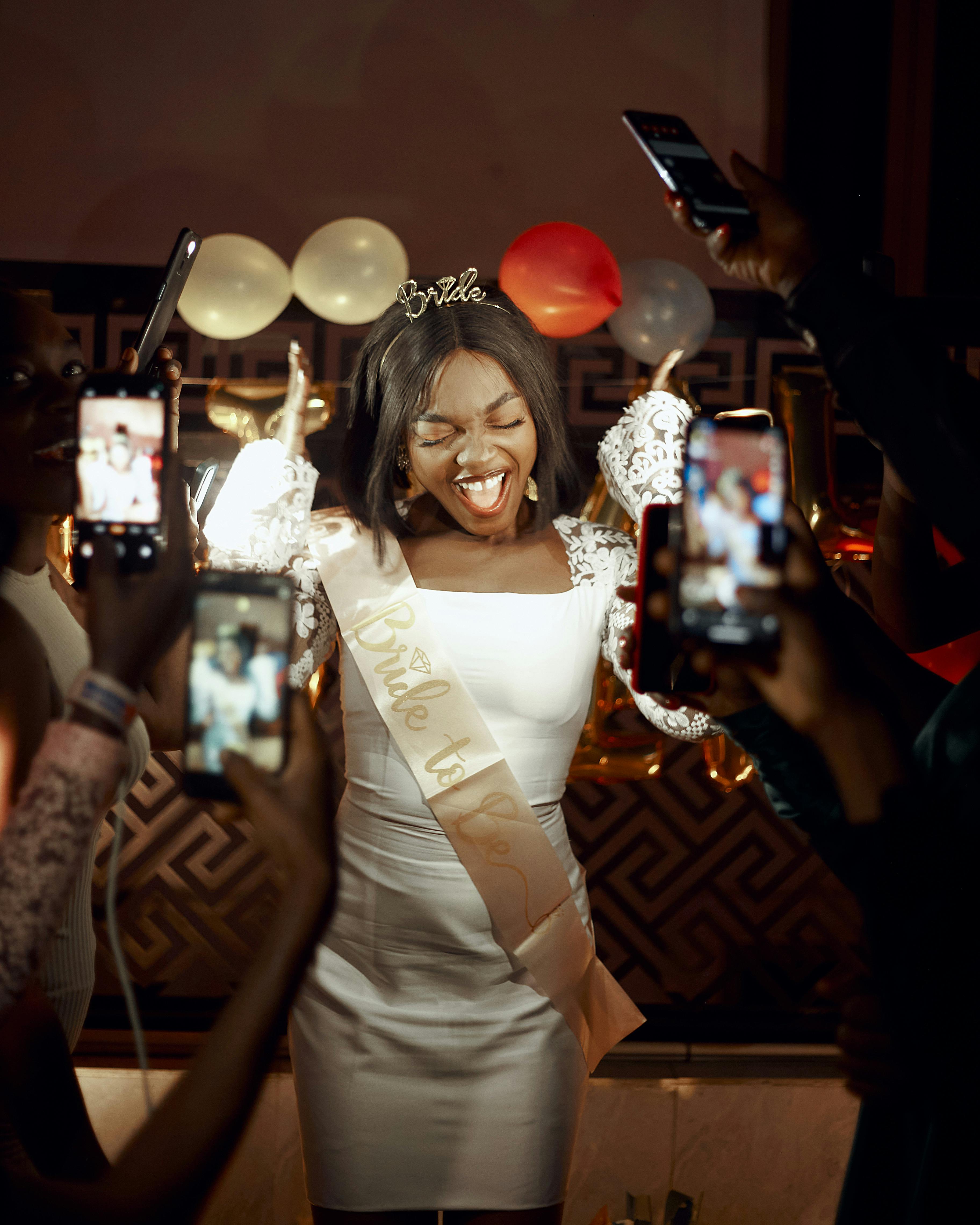 Smiling bride-to-be surrounded by friends capturing her joy at a bachelorette party.