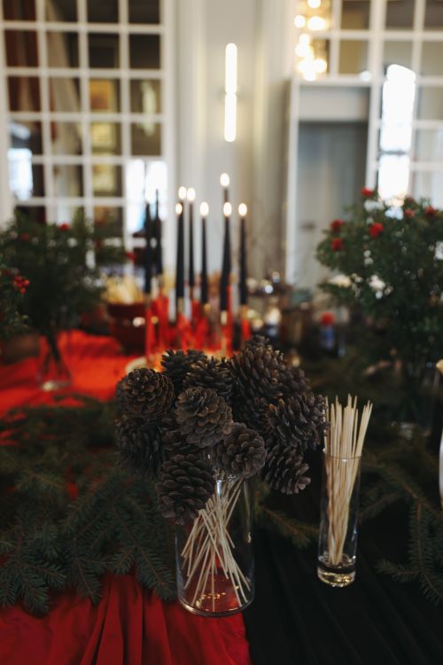 Free A festive holiday table setting featuring pinecones, candles, and greenery indoors. Stock Photo