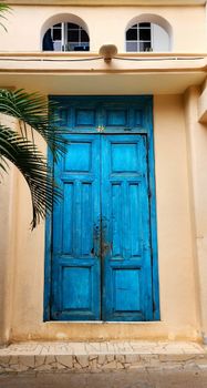 A vibrant blue wooden door on a coastal-style building entrance with tropical accents.